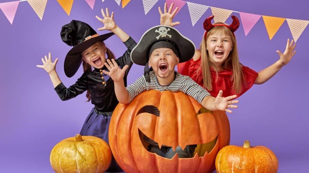 Crianças fantasiadas. Uma delas está dentro de uma abóbora de halloween.