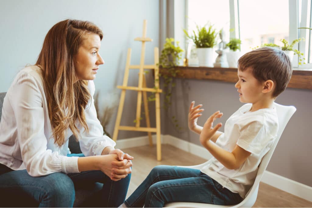 Terapeuta ouvindo atentamente um garotinho falar sentado à sua frente.