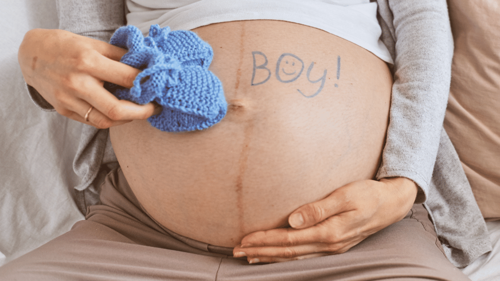 Mulher grávida de menino. Barriga de mulher grávida escrito "É um menino!"
