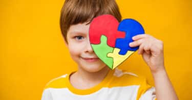 Uma criança segurando um quebra-cabeça em formato de coração.