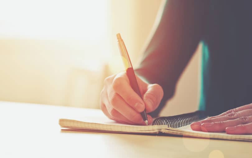 Um homem escrevendo num caderno.