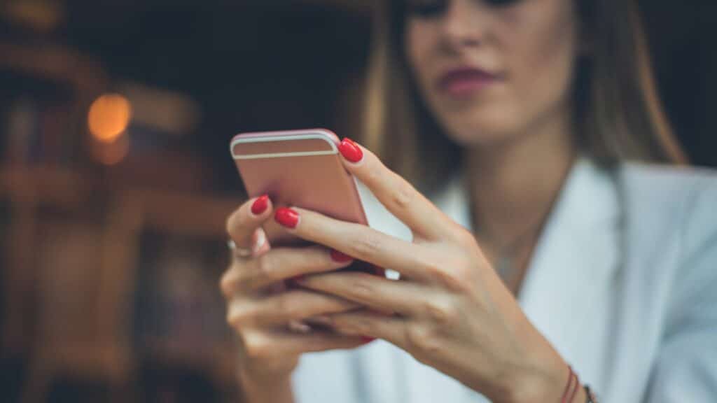 Uma mulher sorridente a manusear um celular.