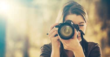 Uma mulher realizando uma captura fotográfica com uma câmera.