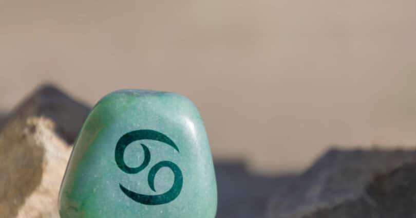 Pedra azul com o símbolo do signo de Câncer desenhado.
