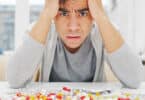 Homem sofrendo de ansiedade com pílulas na mesa