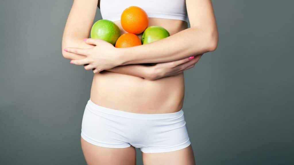 Uma mulher seminua segurando frutas.