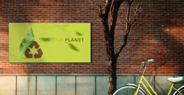 Bicicleta estacionada ao lado de uma árvore aparentemente seca. Ao fundo, na parede, uma placa escrita "Save our planet".