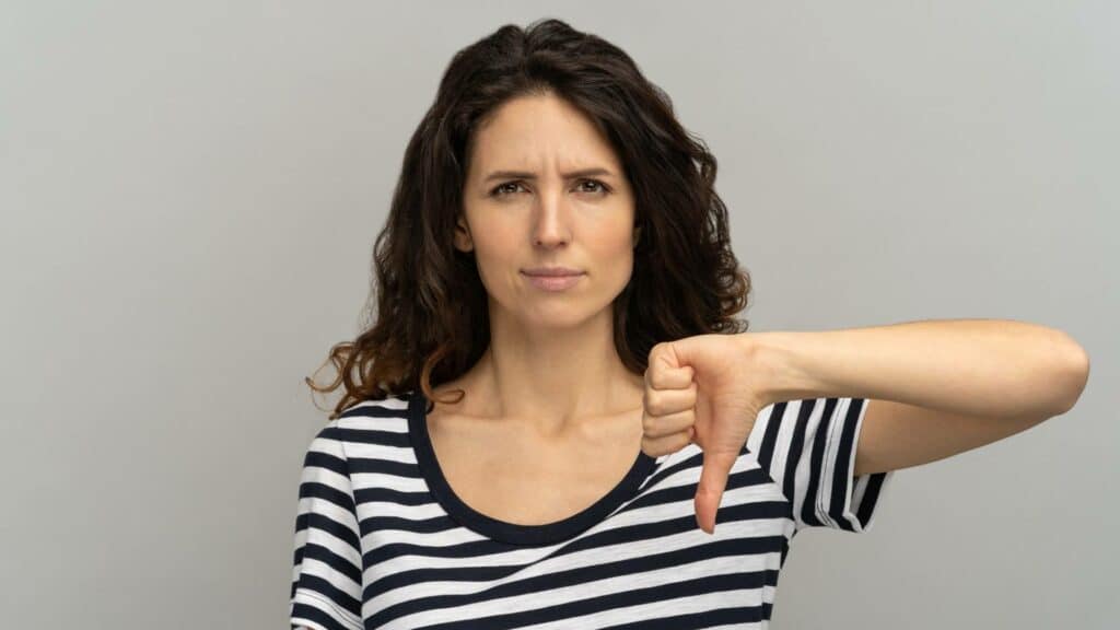 Uma mulher realizando um "joinha" reverso com o seu dedo polegar.
