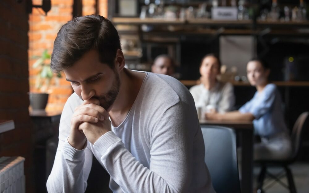 Um homem isolado de um grupo de pessoas.