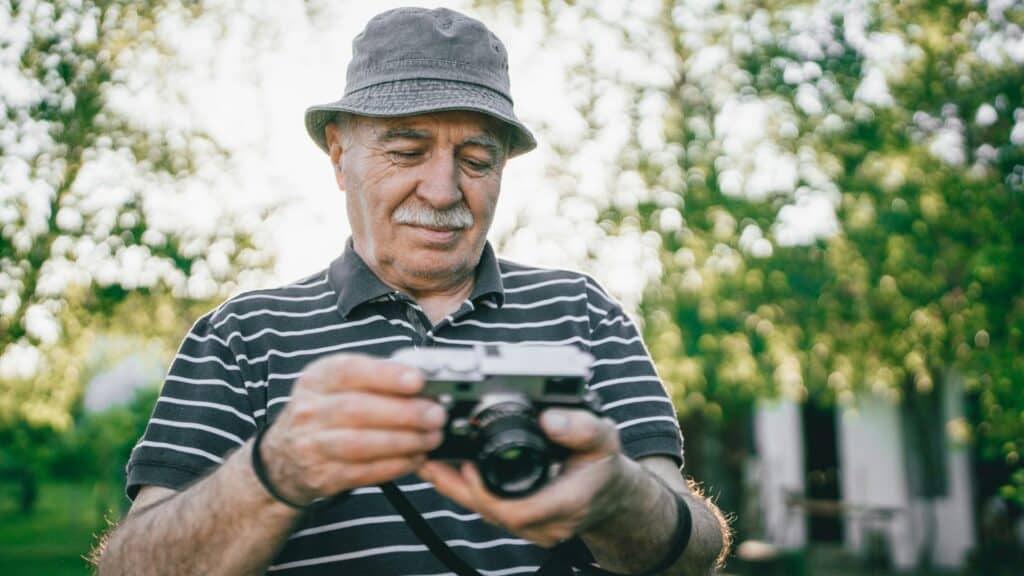 Um homem idoso utilizando uma câmera.