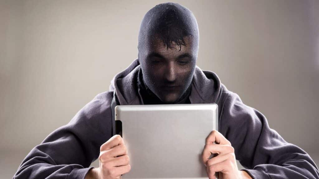 Um homem mascarado utilizando um tablet.