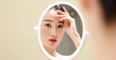 Uma mulher se olhando num pequeno espelho.