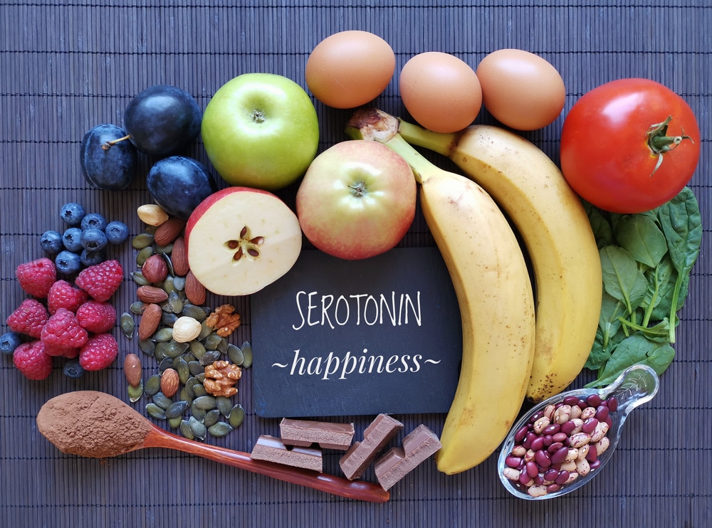 Alimentos reunidos ao redor de uma plaquinha onde está escrito "serotonin, happiness".