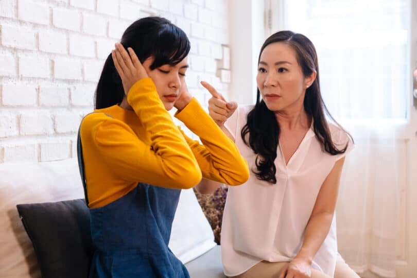 Briga entre mãe e filha asiáticas. A filha está tampando as orelhas
