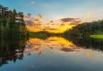 Amazônia: Por do sol com reflexo na água do rio e várias árvores ao redor