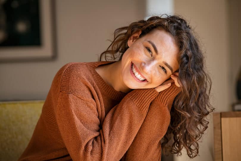 Mulher sorridente com as mãos na bochecha