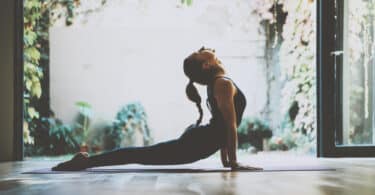 Mulher fazendo yoga com corpo esticado para trás e cabeça levatada