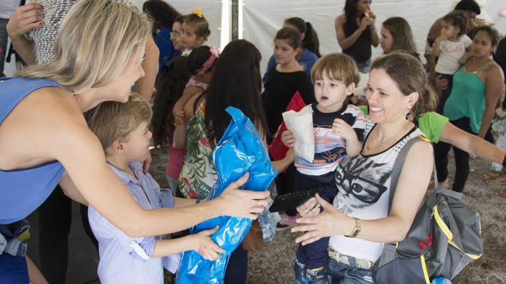 Uma mulher entregando itens numa ação voluntária a outra mulher.