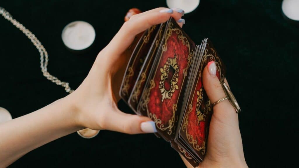 Mãos femininas embaralhando um conjunto de cartas místicas