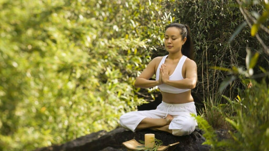 Uma mulher meditando em pleno ar livre.