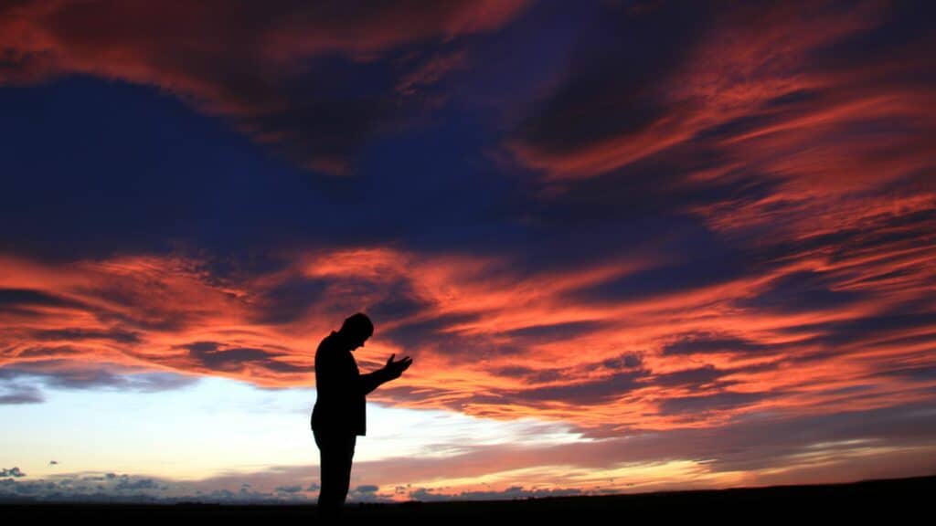Um homem realizando preces ao céu.