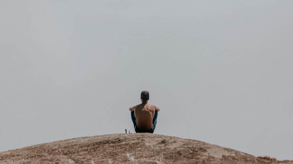 Um homem solitário sentado num cume de areia.