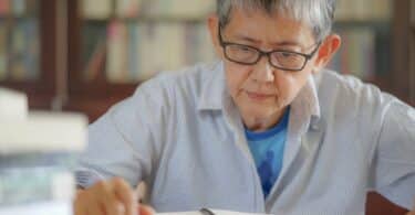 Uma mulher idosa lendo um caderno.