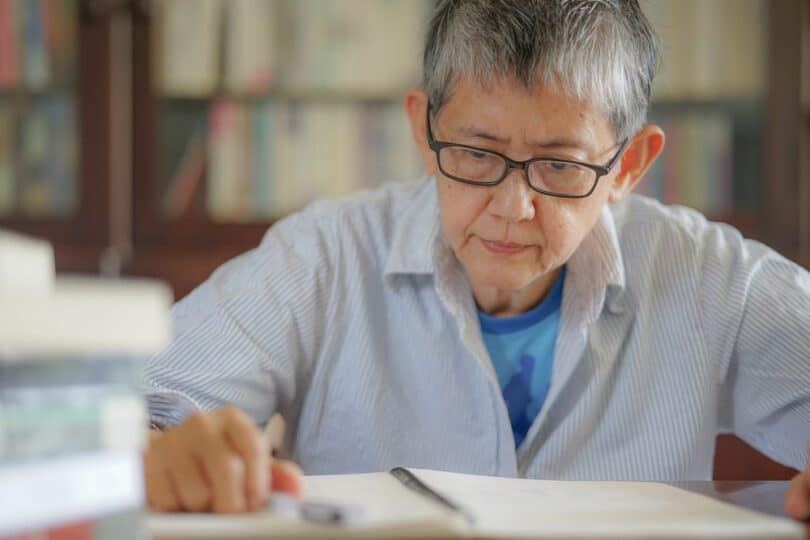 Uma mulher idosa lendo um caderno.