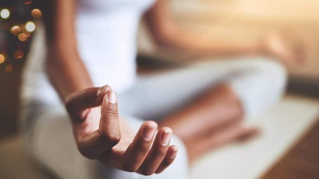 Uma mulher meditando. O enfoque fotográfico é uma das posições de mão típicas da meditação.