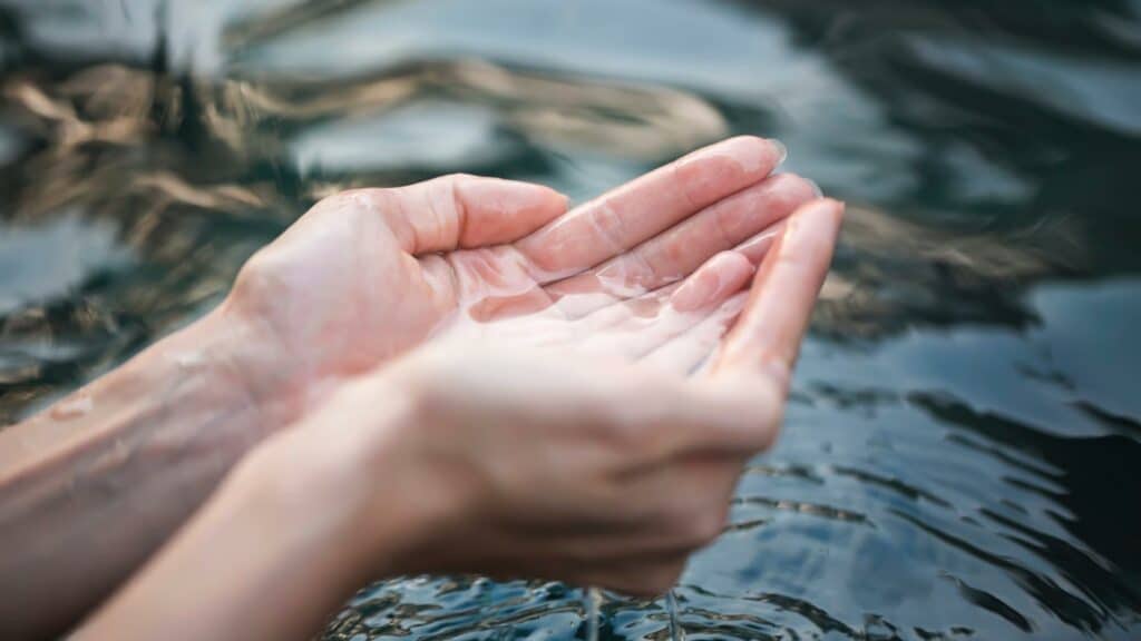 Sobre um rio, mãos em concha comportando água pura.