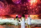 3 Mulheres na praia olhando fogos de artifício.