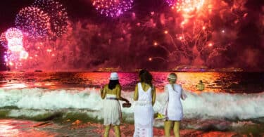 3 Mulheres na praia olhando fogos de artifício.
