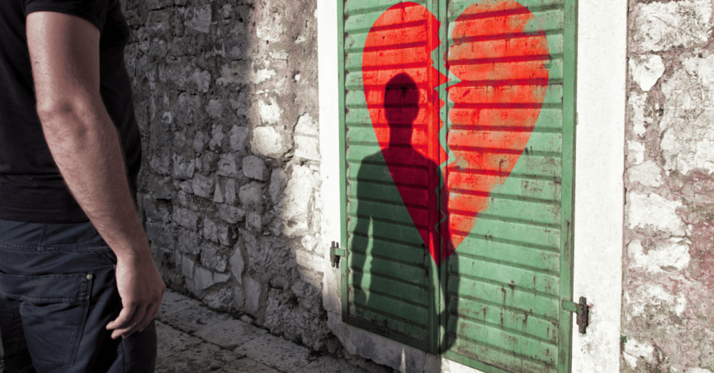Homem olhando própria sombra refletindo em um coração partido.