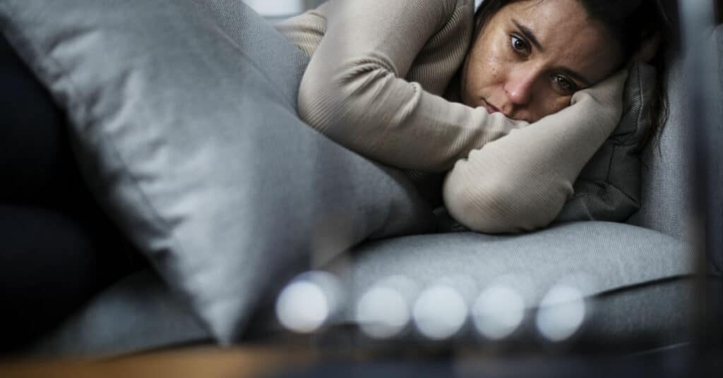 Mulher deitada na cama em estado depressivo.