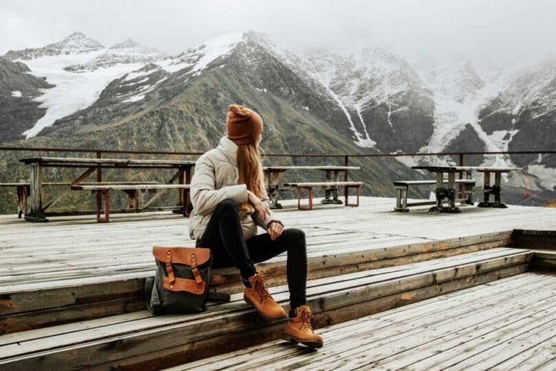 Uma mulher contemplando montanhas repletas de neve.