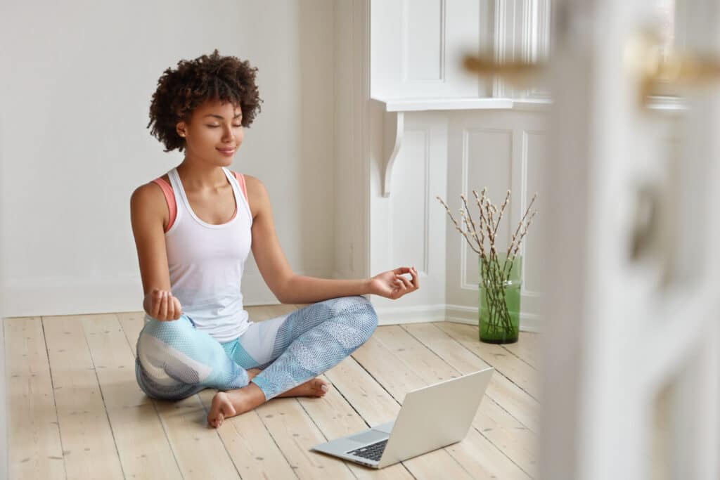 Mulher negra com roupas esportivas meditando