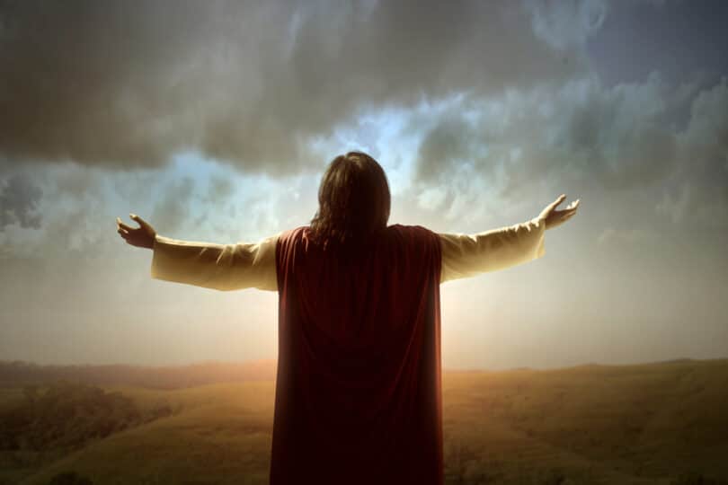 Jesus Cristo de braços erguidos observando o céu.