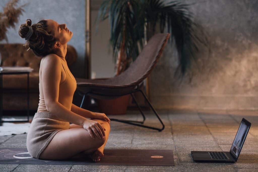 Mulher meditando e alinhando chacras em frente ao computador 