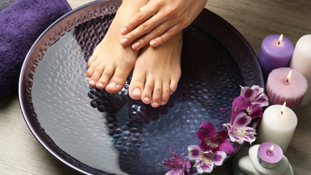 Uma mulher lavando os seus pés numa bacia d'água. À direita dela, velas roxas acesas.