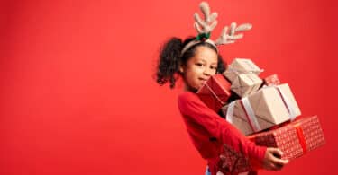 Menina negra com tiara de rena segurando presentes