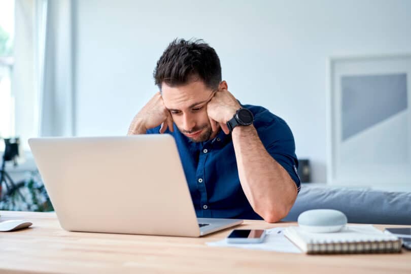 Um homem desanimado olhando um notebook.