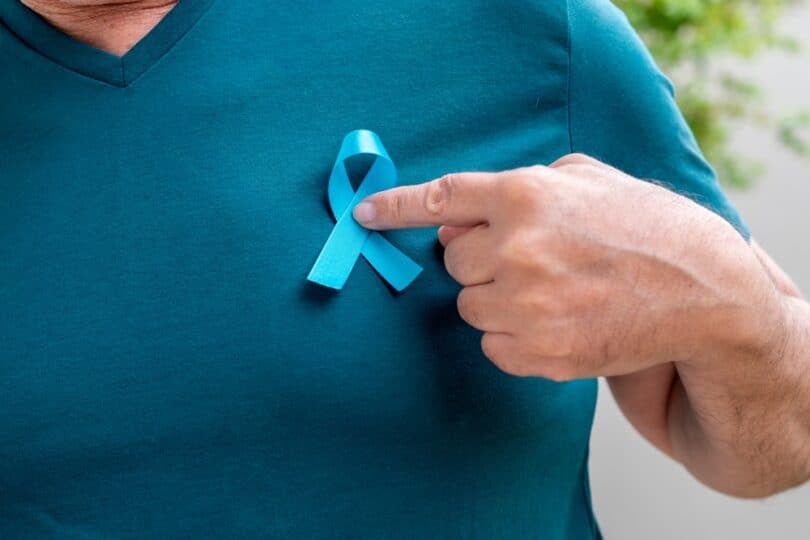 Homem segurando a fita azul no peito