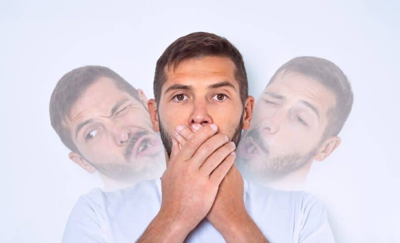Homem segurando a boca enquanto suas sombras fazem caretas involuntárias