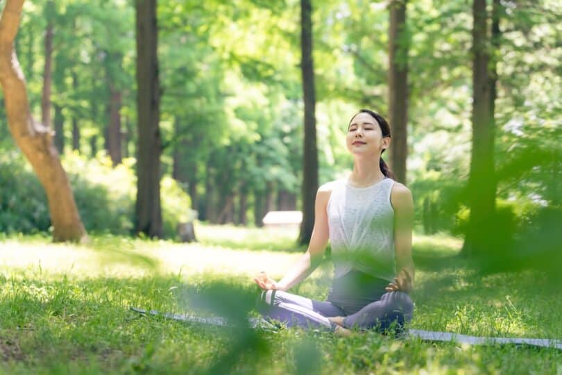 Mulher asiática meditando na natureza