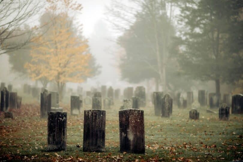 Cemitério vazio, com vários túmulos dispostos em seu terreno. O tempo aparece nublado.
