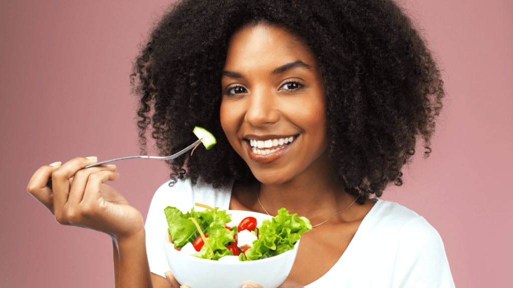Mulher negra comendo uma salada