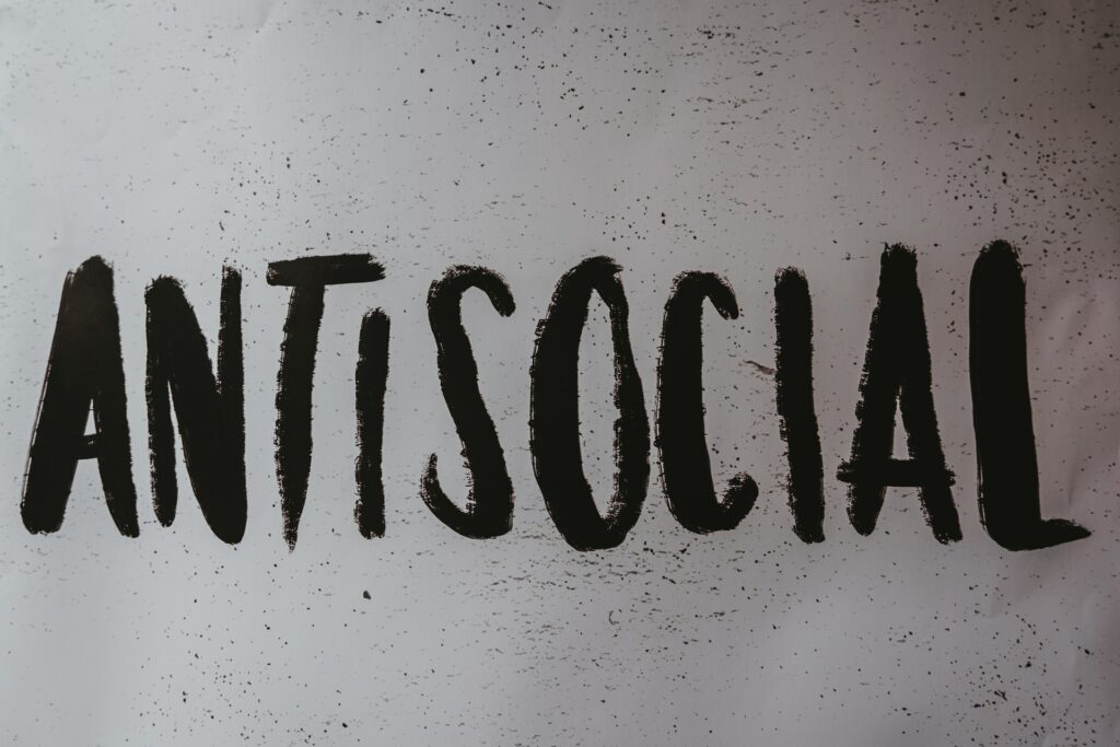 Palavra "antisocial", em inglês, escrita com tinta preta.