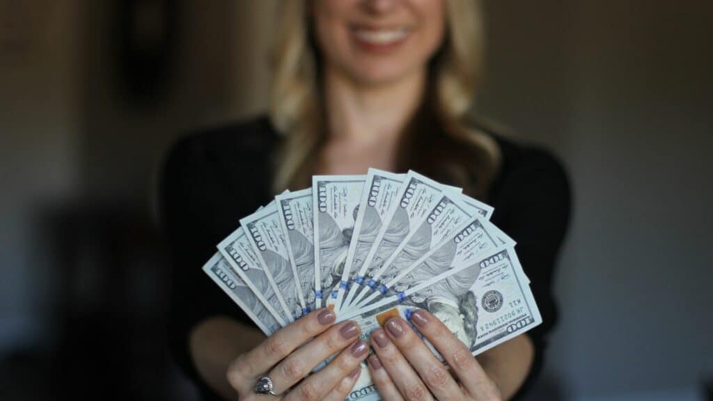 Imagem de uma mulher sorrindo e com notas de dinheiro na mão