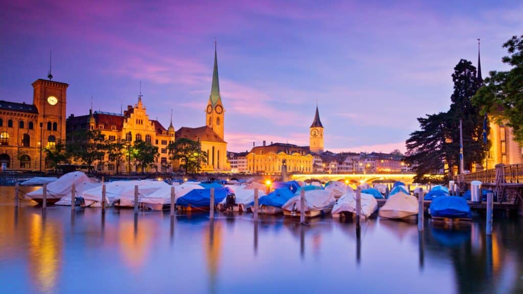 Imagem do Rio Limmat ao entardecer com céu roxeado em Zurique, Suiça.