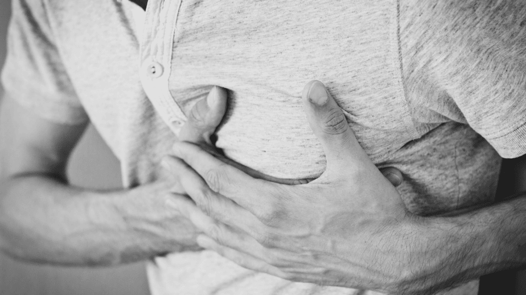 Imagem da mão de um homem segurando o peito.